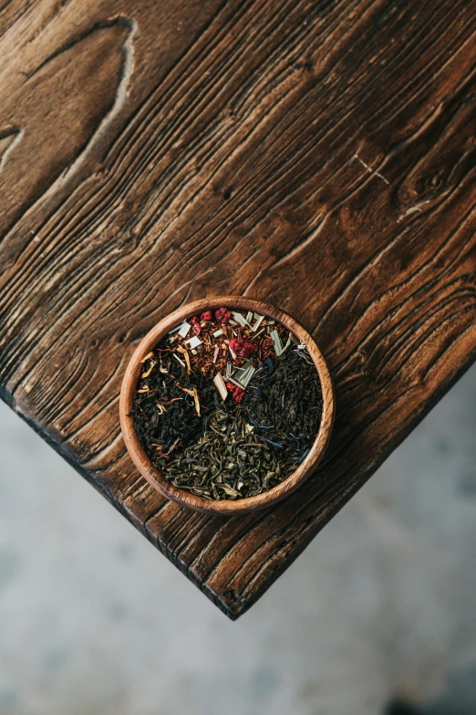 a bowl of colorful flowers is sitting on a wood table