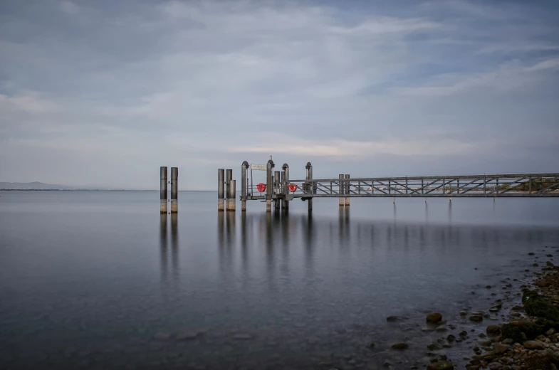 a pier on a lake near some rocks