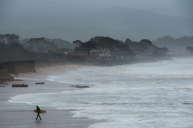 a person with a surfboard walking across the ocean on a beach