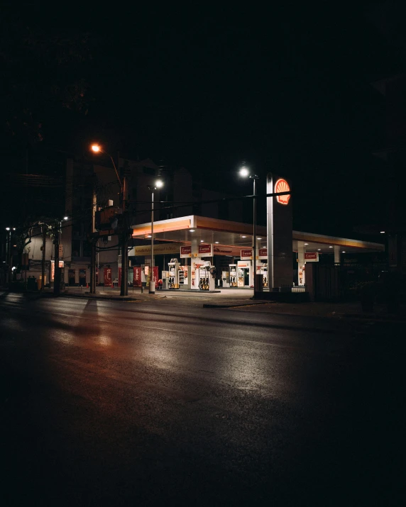 a empty road at night time with a gas station and store on it