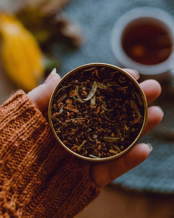 a person holds up a gold colored tea cup