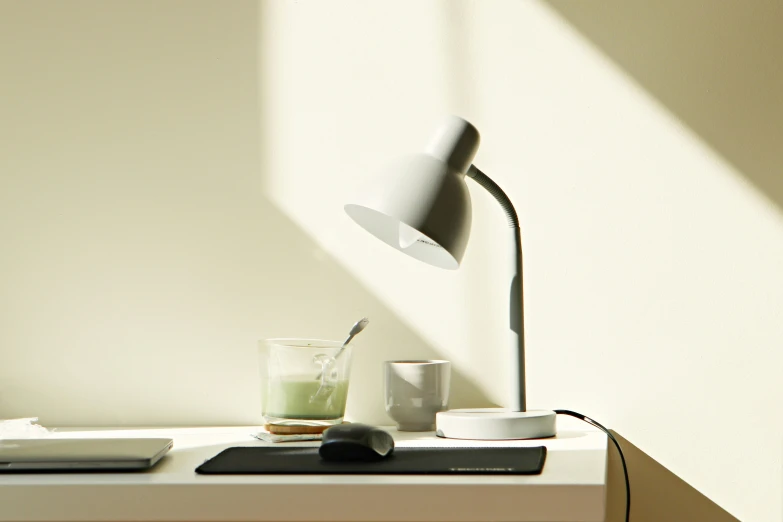 a lamp sits on top of the desk next to a glass and mouse