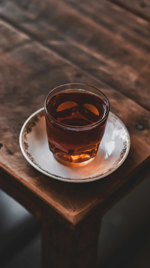 a glass of tea sits on top of a small saucer