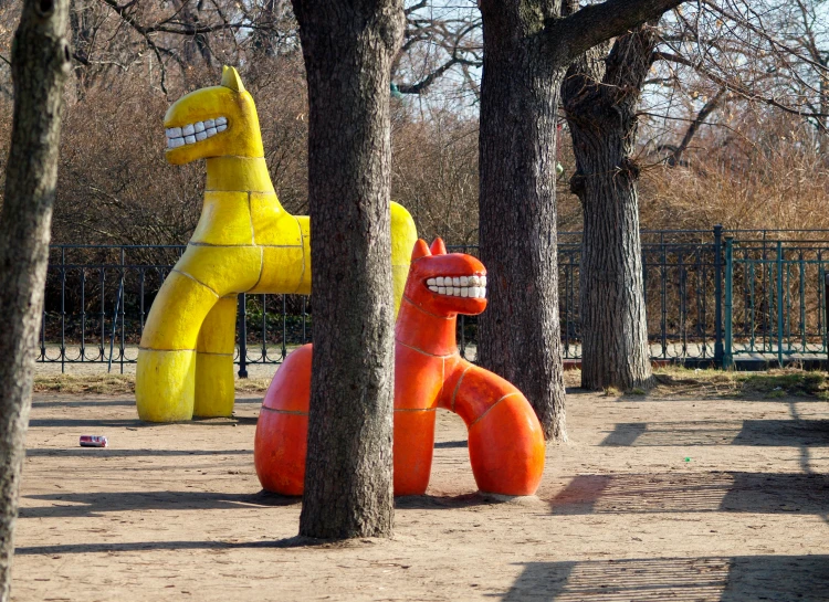 a park has some giant yellow and orange figures sitting on the ground