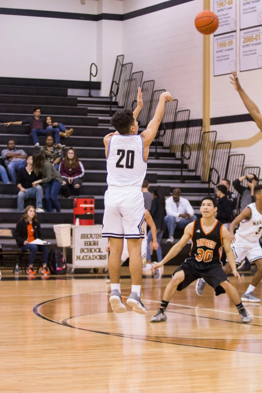 a young man holding a basketball up while standing on a basketball court