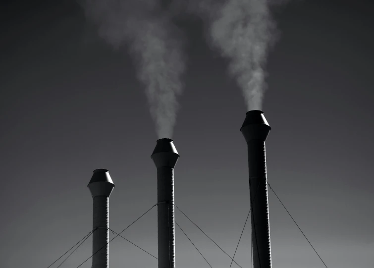 smoke stacks rising from the top of chimneys with wires below