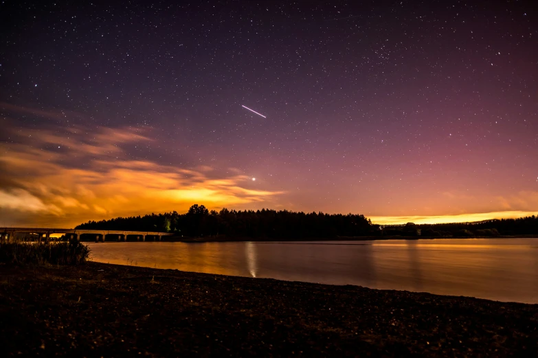 the stars above the lake and trees glow in the dark