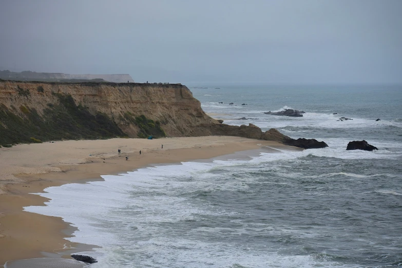 an ocean with waves crashing onto the shore near a rocky shoreline