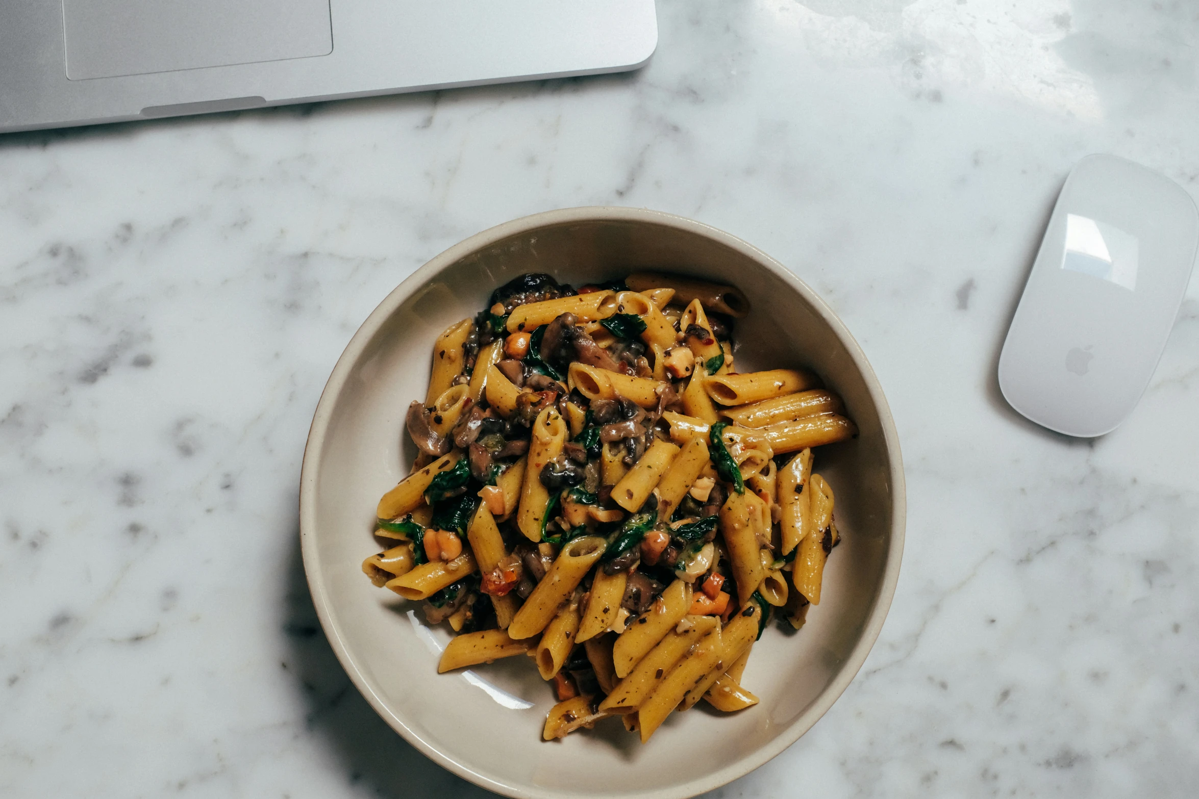 a plate of pasta is sitting next to a computer mouse