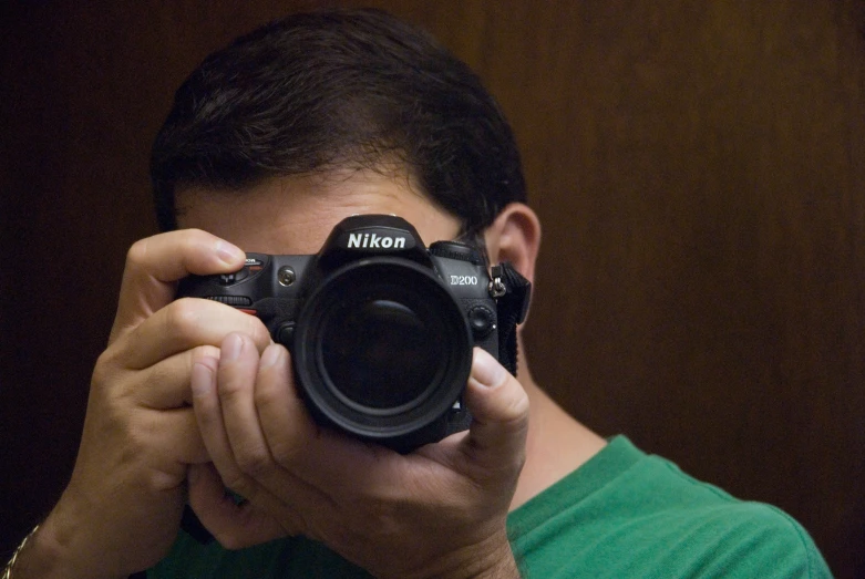 a man in green shirt holding up a camera