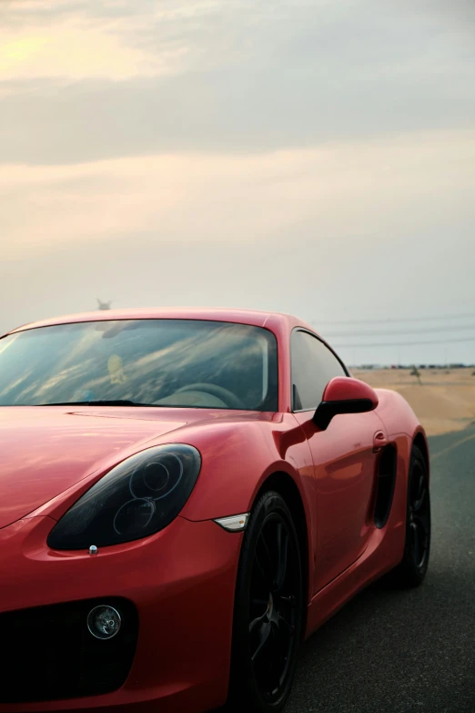 a red sports car driving down the road in front of water