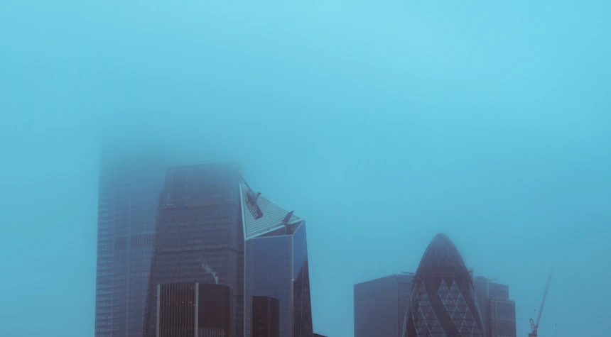 a group of tall buildings with fog in the air