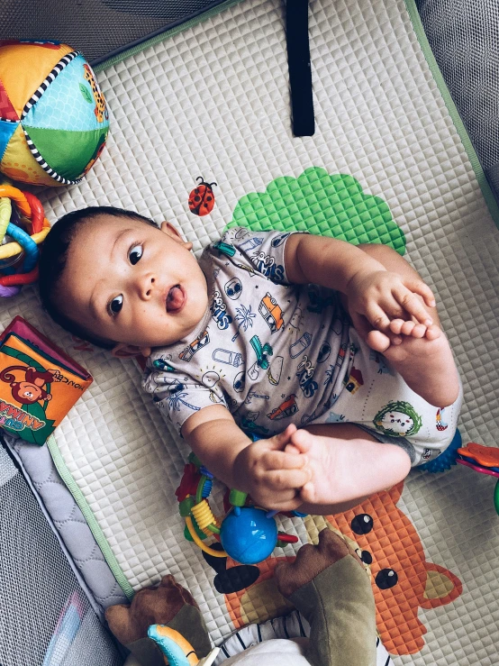 the baby is laying down on the floor near toys