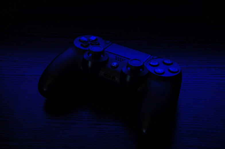 blue lights shining onto a gaming controller on black table