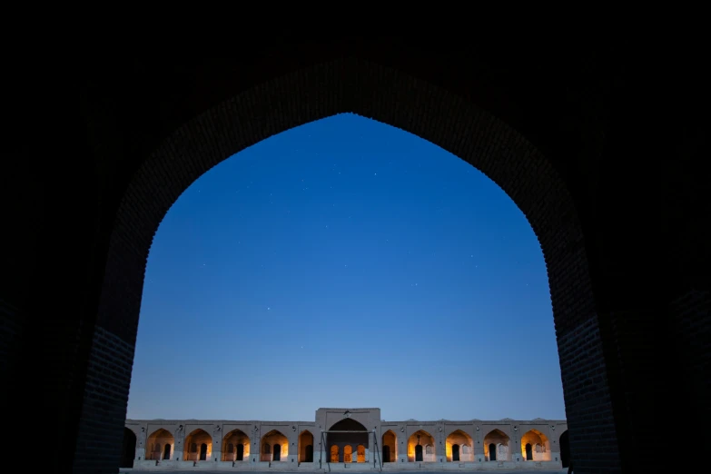 the moon shines brightly over an arched window