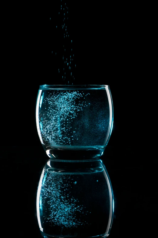 a glass full of water is sitting on a black surface