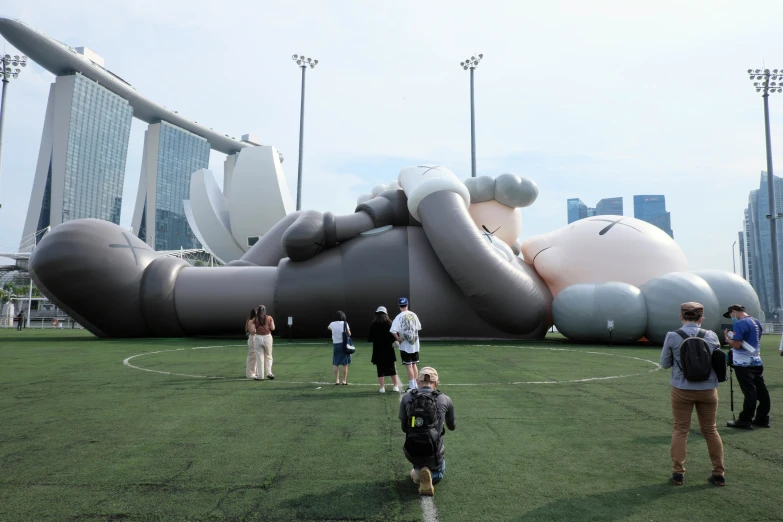 people are standing in the grass near a large balloon on the field