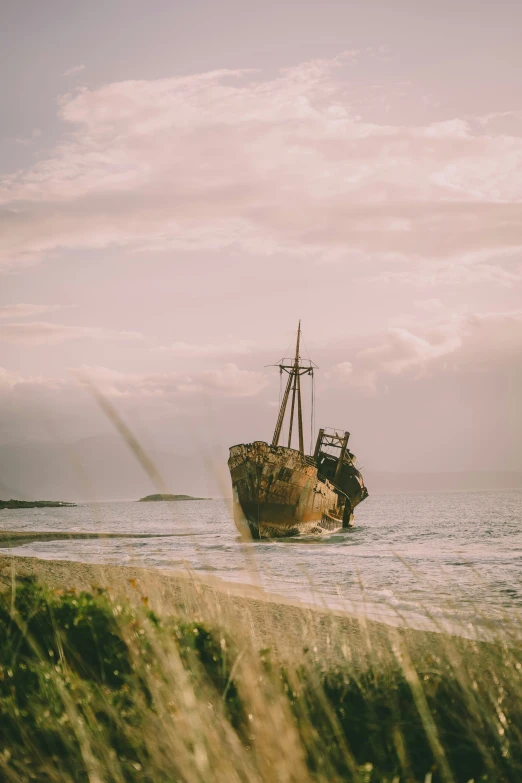 an abandoned boat sitting in the water on a beach