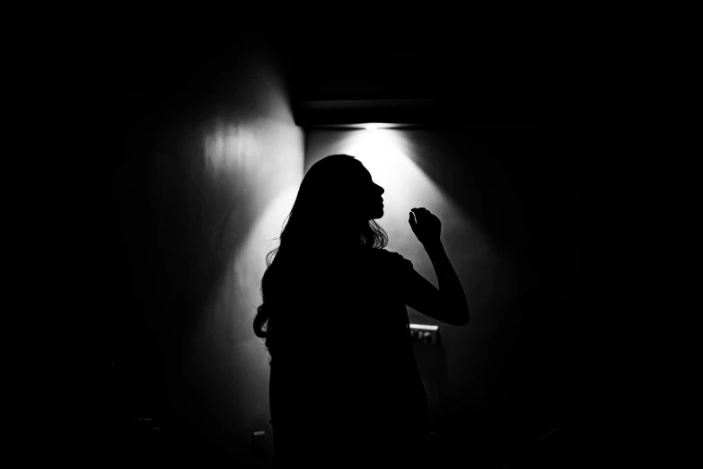 a woman is standing in a dark room with her back light on