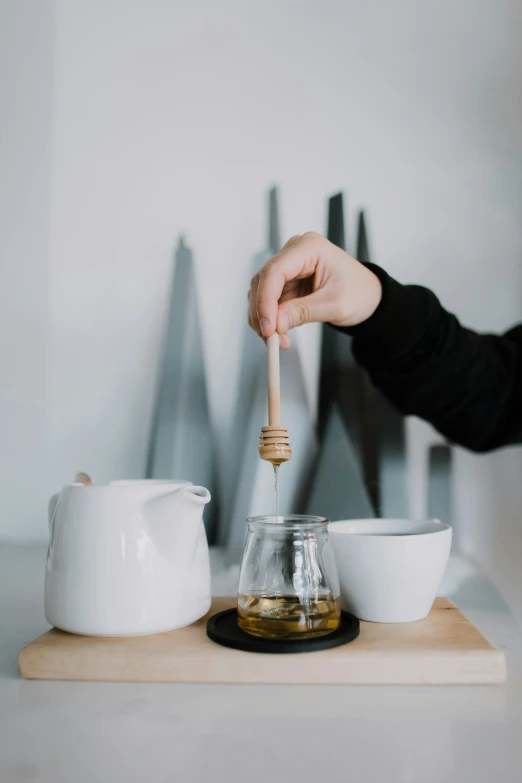 a person holding a wooden spoon over a small cup