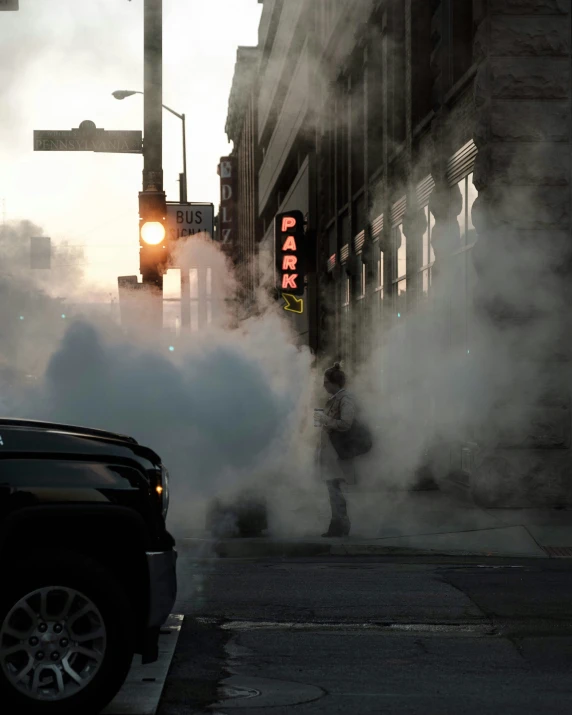 some smoke is surrounding a black car on the street