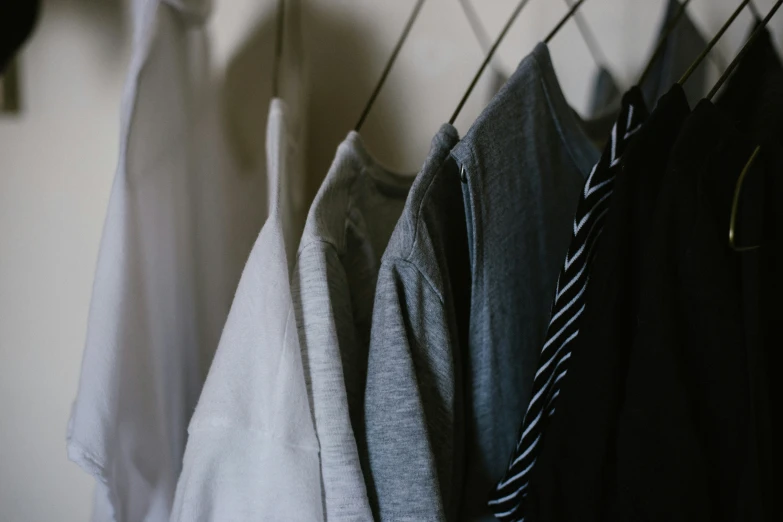 various sweaters hanging from a rack and clothing