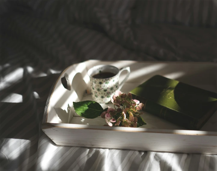an open book with some flowers and a tea cup