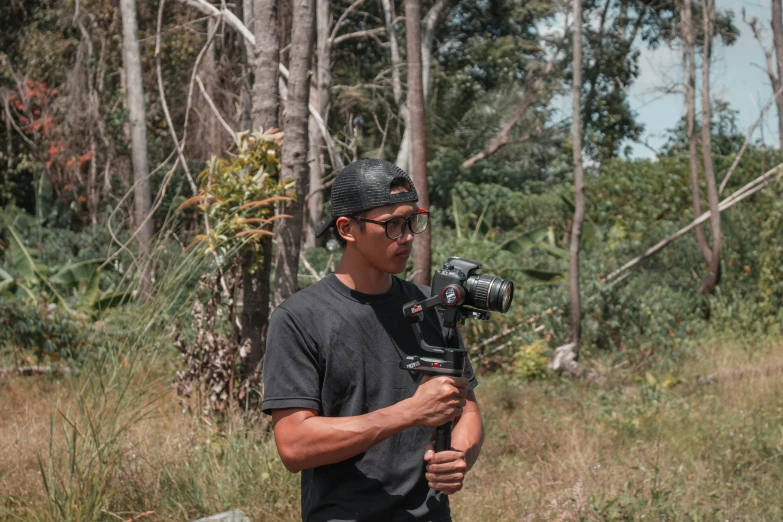 a man holding a camera in front of trees