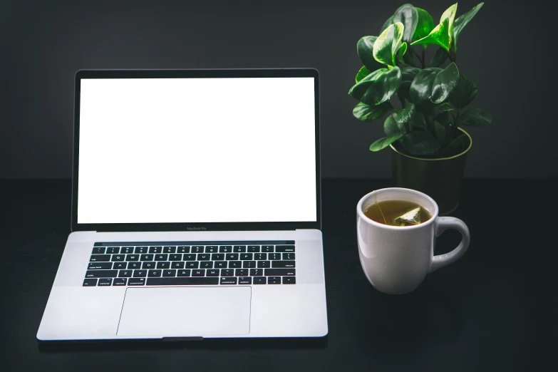 a lap top computer sitting next to a mug of coffee