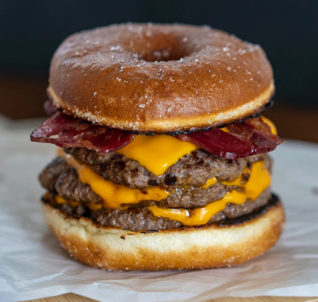 a hamburger with bacon and cheese is in a white paper bag