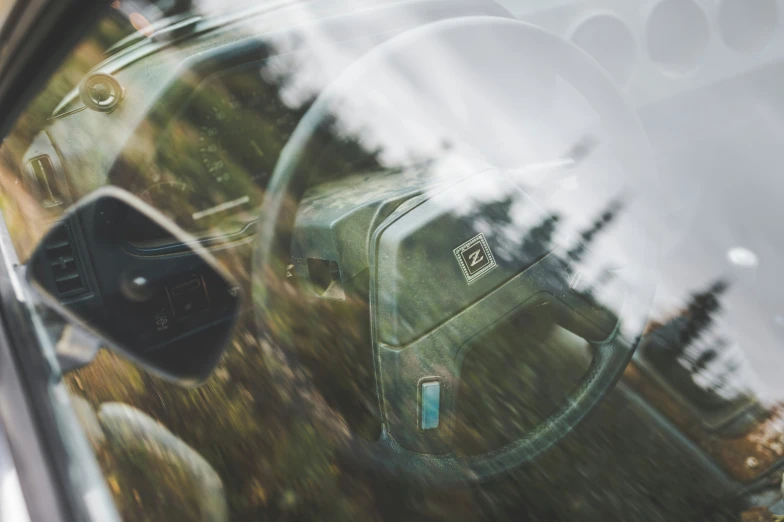 the rear view mirror of a green car looking at trees