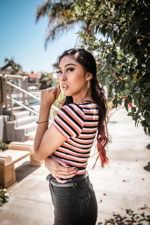 woman wearing striped shirt posing by stairs under tree