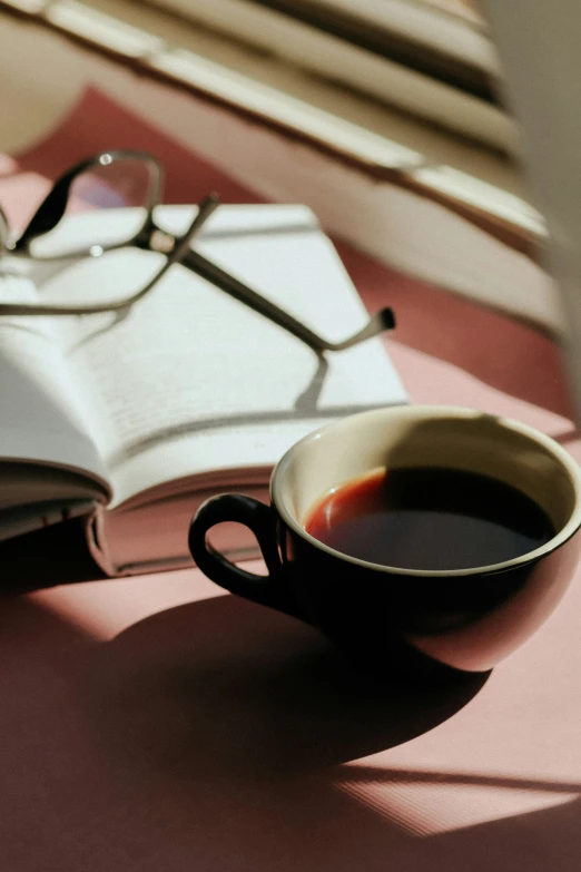 a cup of coffee sits next to an open book