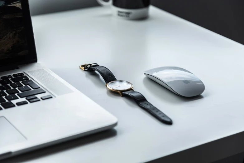 there is a mouse on the desk with a wrist watch next to the computer