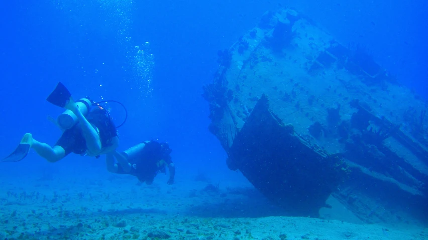 scubars are diving under the wreck on the ocean floor