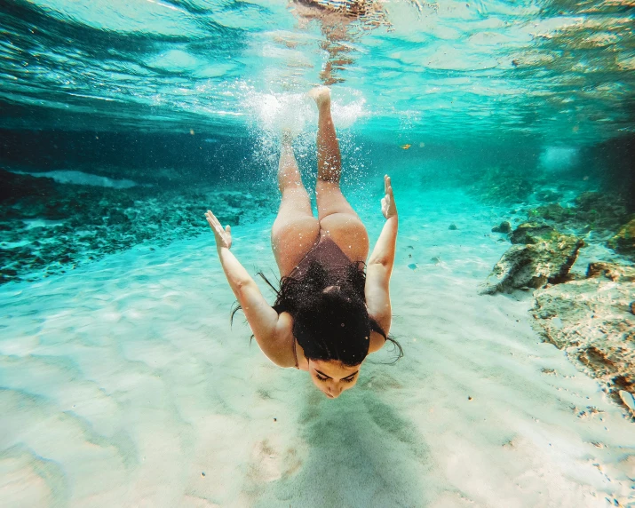 a woman dives under the water near the beach