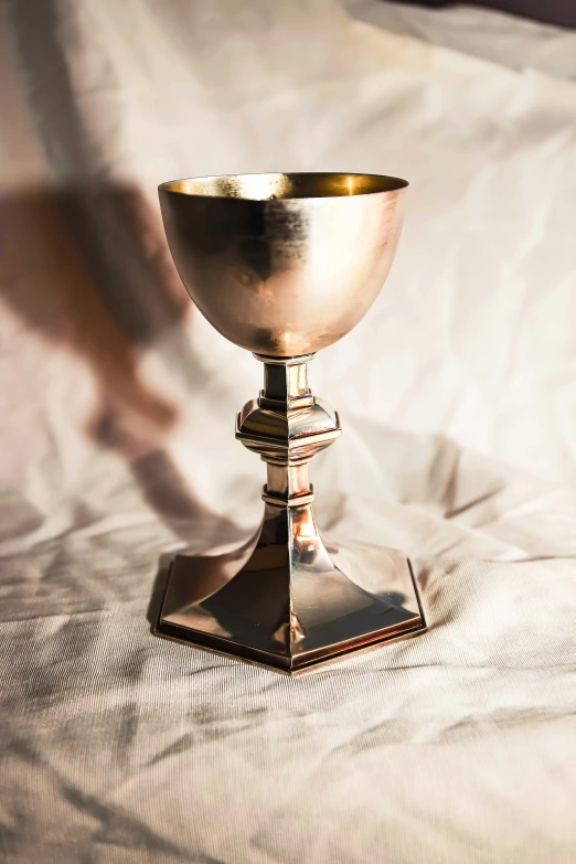 the shiny gold chalice is displayed on the white sheets