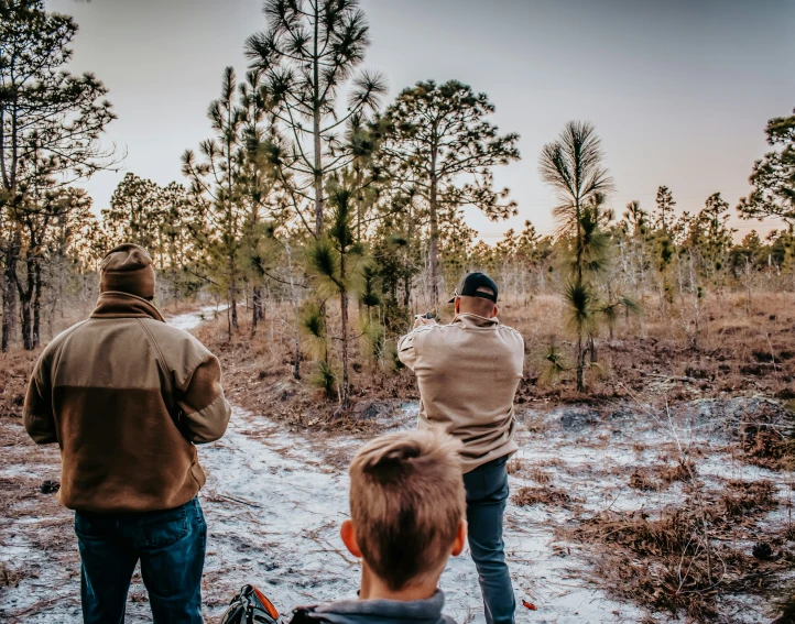 a few men standing in the snow with one boy watching them