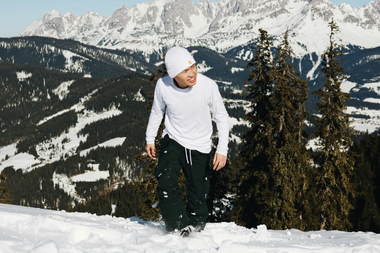 a snowboarder in white shirt standing on snowy slopes