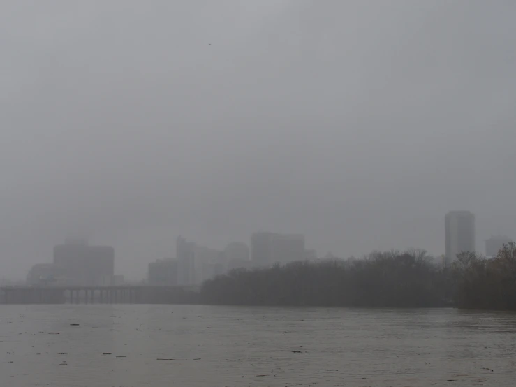 a boat traveling on a river near tall buildings in the distance