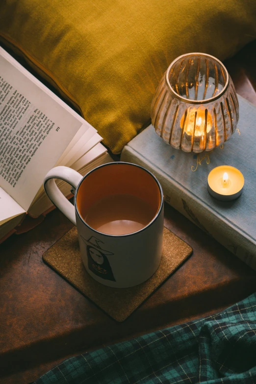 the coffee cup is on the table beside an open book