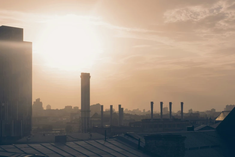 city skyline and clouds in the foreground with sun coming through the sky