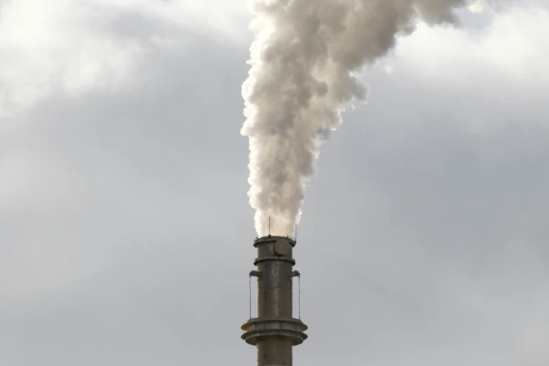 a tower with a smokestack is emitting steam into the sky