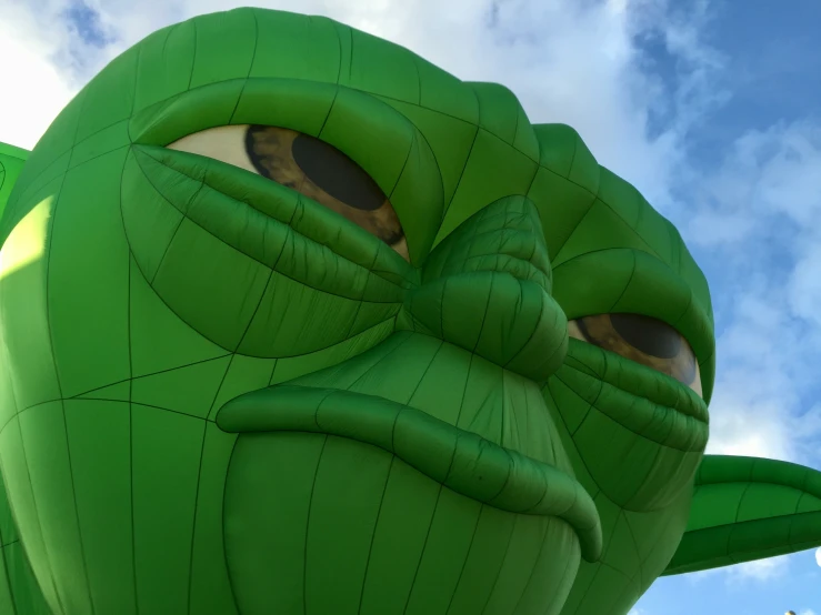 the head of an inflatable green frog flying through the air