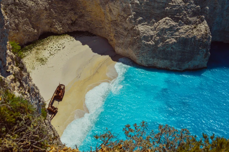 two brown boats on a beach with some rocks