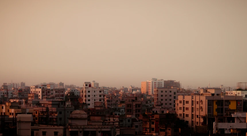 a group of buildings in the distance are under a hazy sky