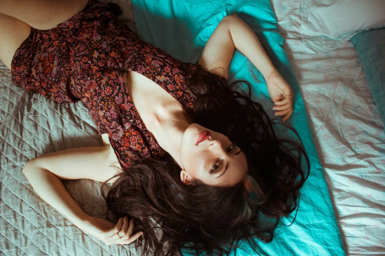 a woman laying on top of a bed near her pillow