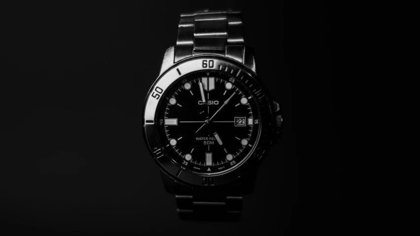 a stainless steel watch is sitting in the dark