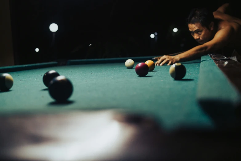 a man playing pool in a dark room