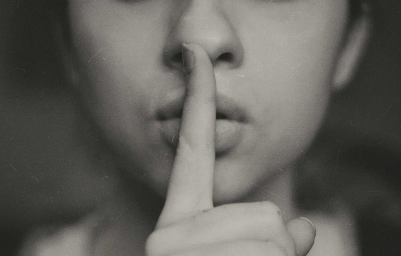 a black and white po of a person with her finger on their lips